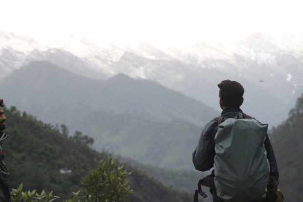 man with gray backpack across mountain