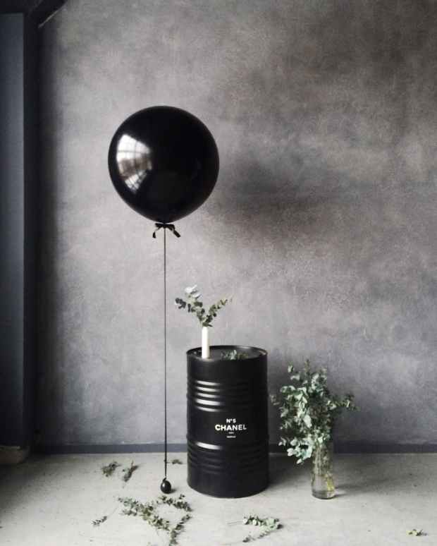 grayscale photography of balloon beside chanel metal barrel